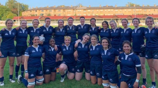 The women's Varsity rugby team pose on the pitch for a photo.