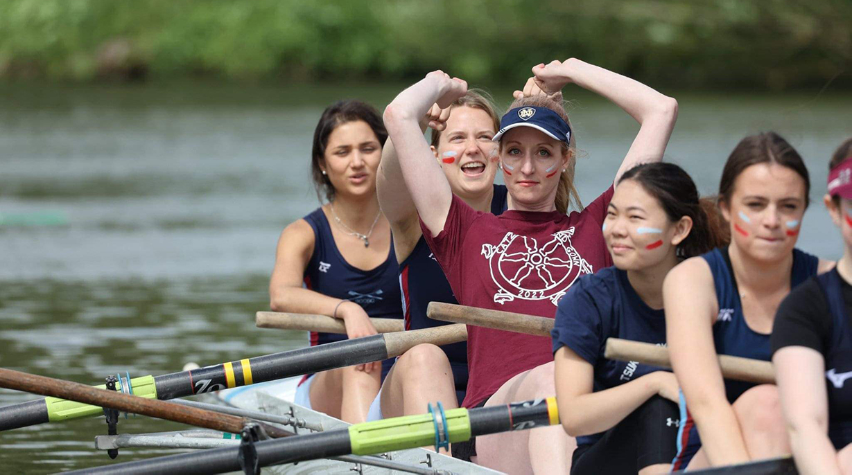 A close-up of the women's boat club celebrating on the river