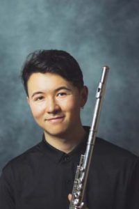 Daniel Shao smiles and holds a flute.