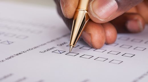 A close-up image of a pen filling in a survey.